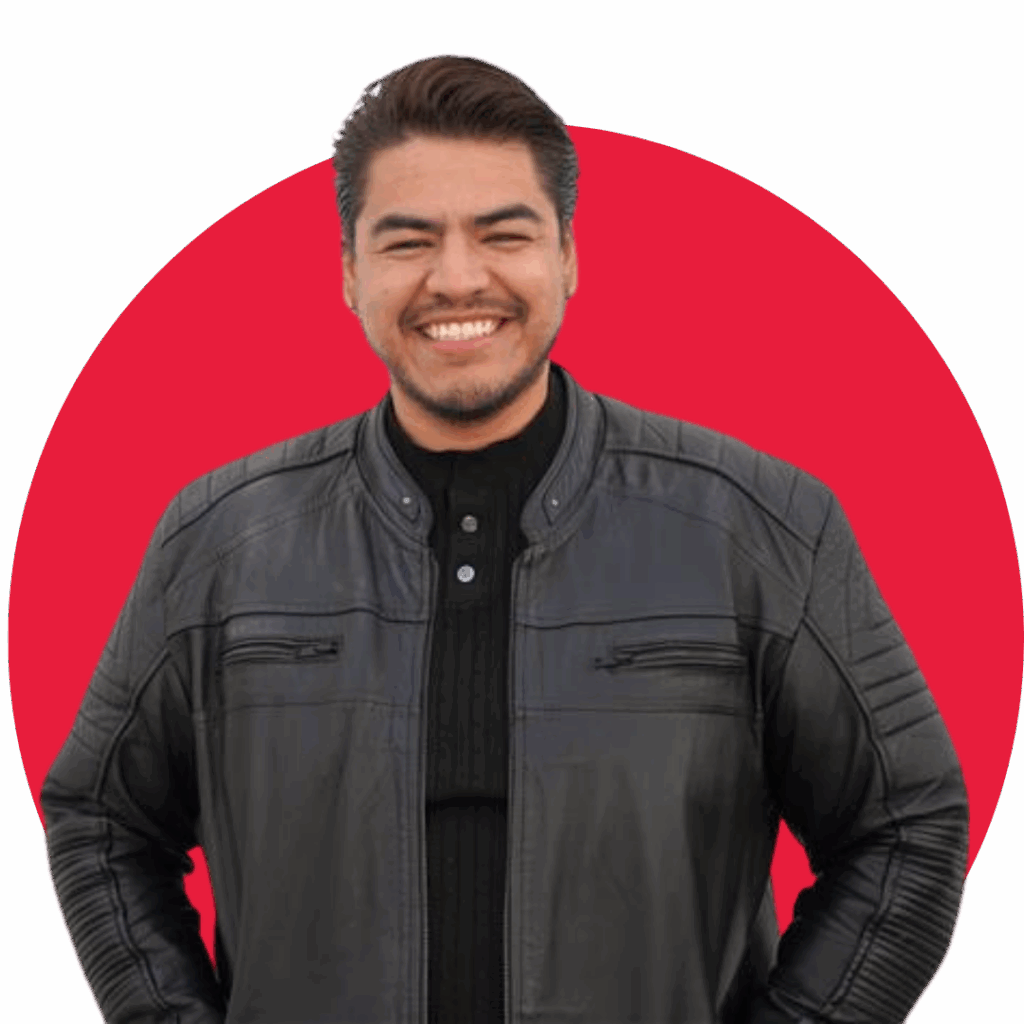 Diego Sepulveda smiles while standing in front of a solid red circular background. He is wearing a black leather jacket over a black shirt, facing the camera with a relaxed and confident posture.